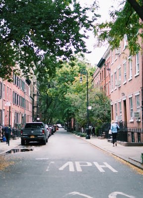 Tree-lined cobblestone street with brick buildings in the West Village