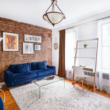 Cozy NYC apartment with exposed brick wall and blue sofa