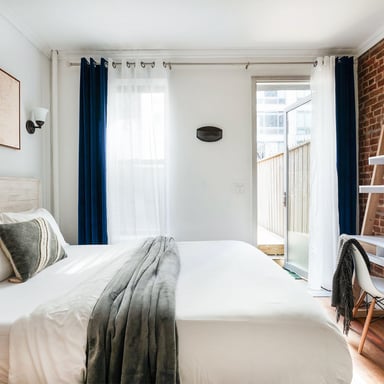Cozy NYC bedroom with exposed brick wall and balcony access