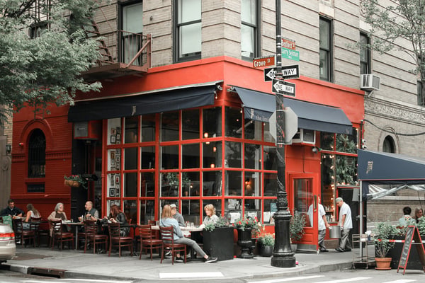 Red corner restaurant with outdoor diners in the West Village